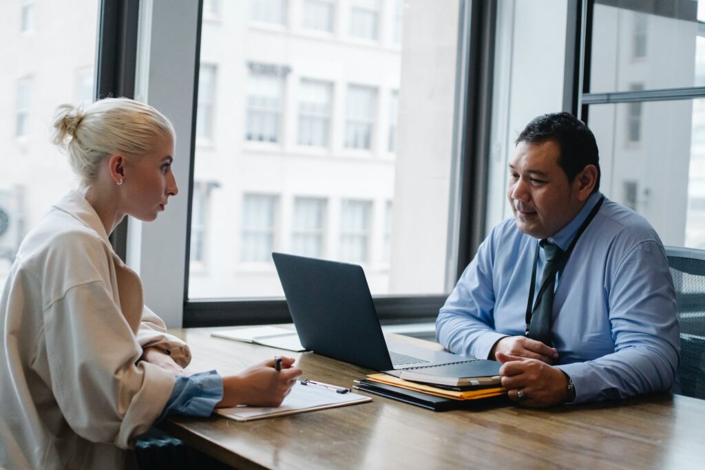 Woman taking notes while talking to an interviewer.