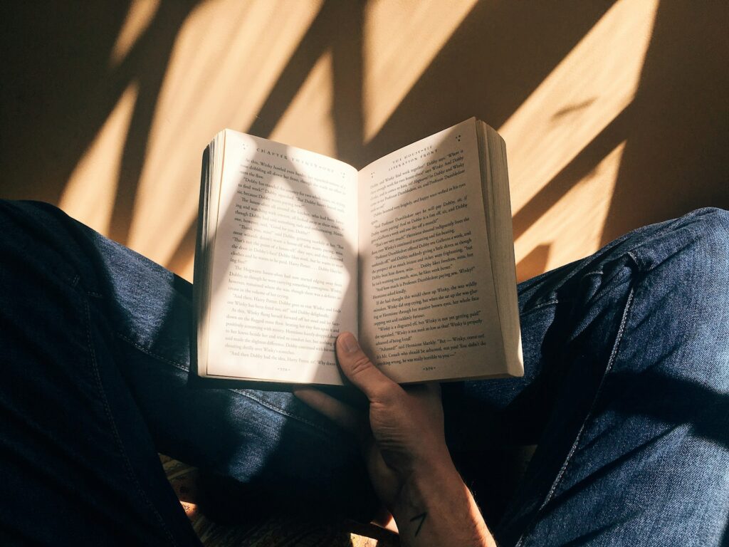 Person reading a book while sitting on the floor.