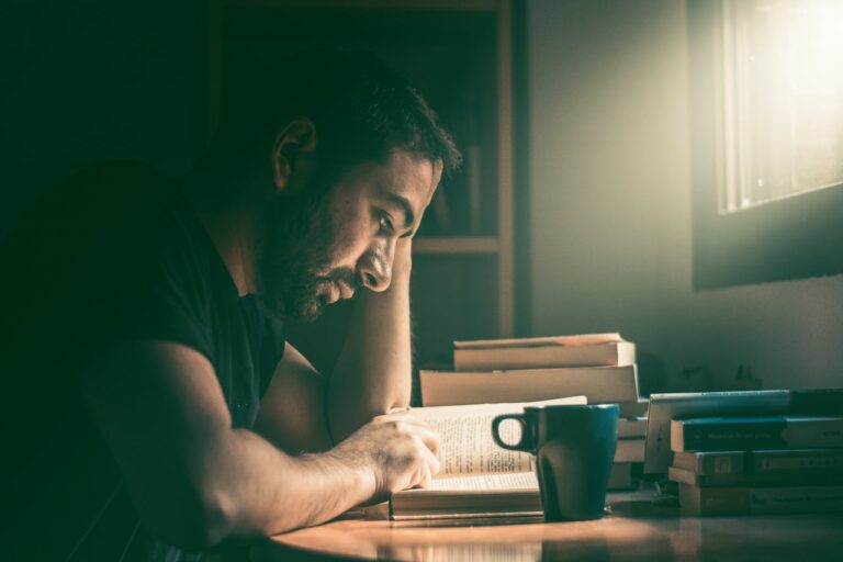 Man sitting at a desk and reading a book.